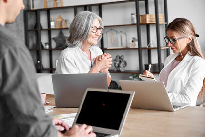 zwei Personen sitzen an einem Tisch mit einem Laptop