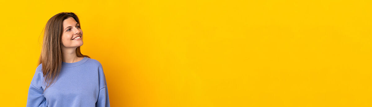 eine Frau, die gegen eine gelbe Wand steht