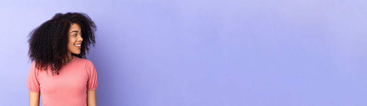 eine Frau, die mit den Händen an den Hüften an einer Wand steht